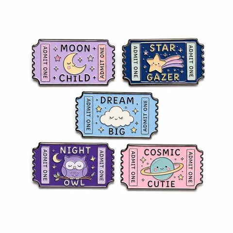 Five pastel and navy ticket-shaped pins with moon, star and space illustrations